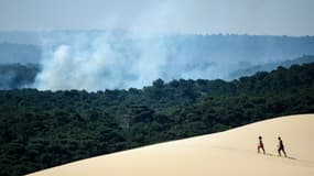 Deux personnes sur la la dune du Pilat d'où l'on voit la fumée s'élever de l'incendie qui s'est déclaré à La Teste-de-Buch (Gironde), le 16 juillet 2022 