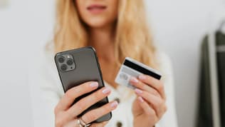 Une femme avec un smartphone et une carte bancaire (illustration)