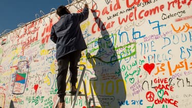 Un migrant inscrit un message sur un mur du terminal de ferry de Calais (photo d'illustration) -