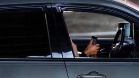 Image d'illustration d'un conducteur avec son téléphone portable à la main