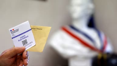 Un électeur tient sa carte électorale et son bulletin de vote face au buste de Marianne, dimanche 19 juin 2022, lors du second tour des élections législatives