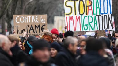 Des manifestants brandissent des pancartes alors qu'ils participent à un rassemblement contre la loi sur l'immigration récemment adoptée par la France, à Paris le 21 janvier 2024.