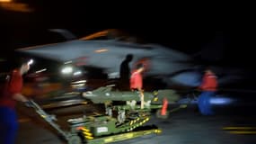 Des marins français chargent un chasseur Rafale avec un misile à guidage laser en vue d'une mission en Irak ou en Syrie