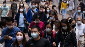 Des passants portant des masques par précaution face au Covid-19, le 30 octobre 2021, dans une rue de Hong Kong 