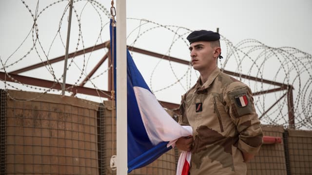 Un soldat français de l'opération Barkhane porte le drapeau français, descendu du mât, à l'issue d'une cérémonie de remise de la base militaire de Barkhane à l'armée malienne à Tombouctou, le 14 décembre 2021. 