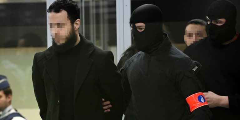 Salah Abdeslam (g), Osama Krayem et Mohamed Abrini escortés par des policiers jusqu'au box des accusés lors du procès des attentats jihadistes de 2016, le 3 avril 2023 à Bruxelles