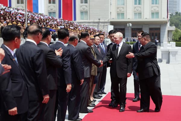 Le dirigeant nord-coréen Kim Jong Un regarde le président russe Vladimir Poutine serrer la main de représentants officiels lors d'une cérémonie de bienvenue sur la place Kim Il Sung à Pyongyang, le 19 juin 2024.