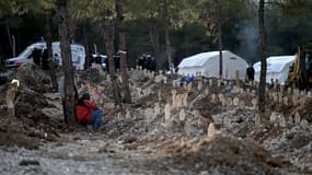 Un homme est assis près d'un cimetière mis sur pied pour accueillir les dépouilles des victimes du séisme du 6 février 2023.