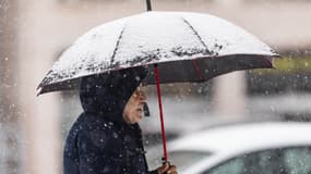 Un homme s'abrite avec un parapluie lors de chutes de neige à Lille, le 17 janvier 2024