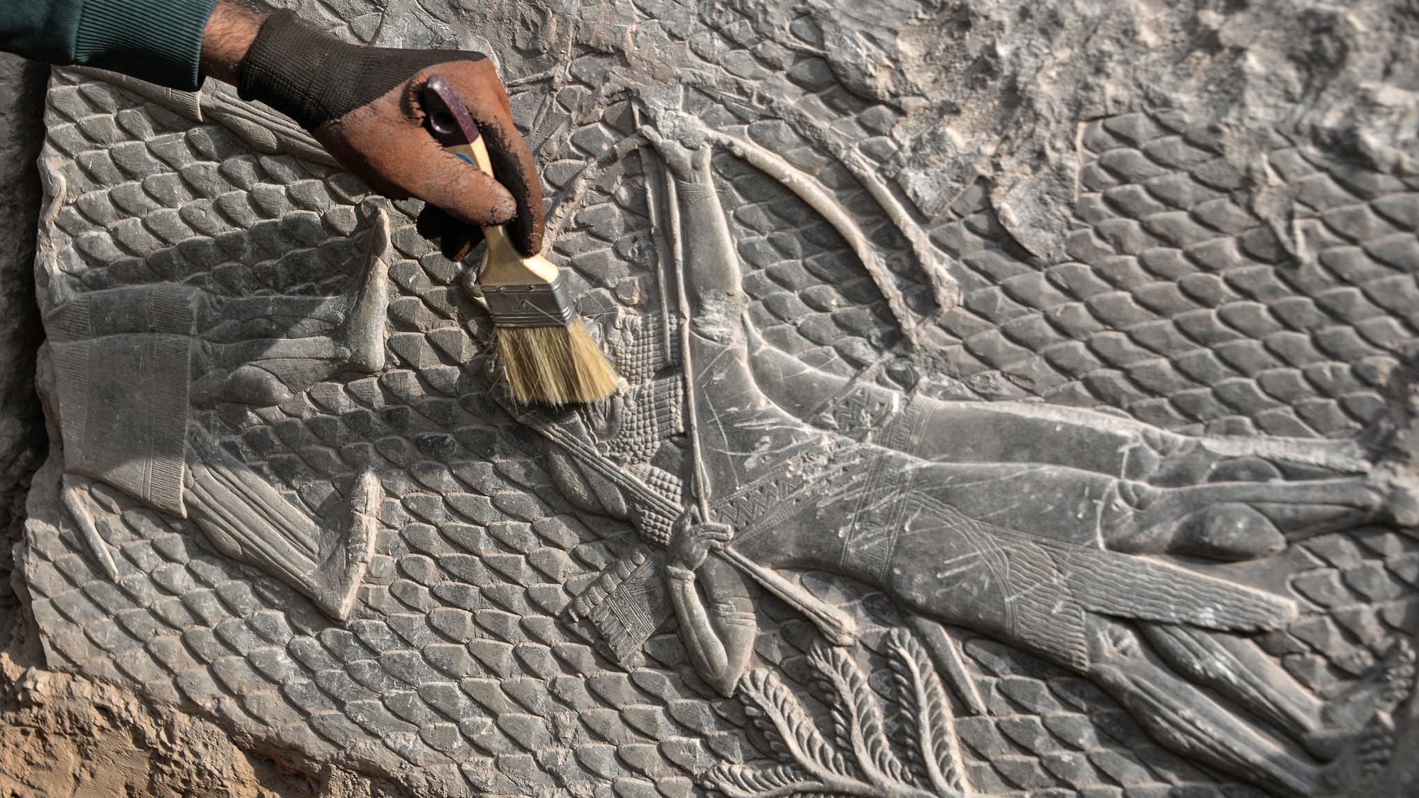 Un travailleur irakien met en lumière un bas-relief découvert à Mossoul, vieux de 2700 ans et représentant des scènes de guerre de l'époque des puissants rois d'Assyrie