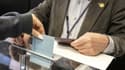 Une électrice française met son bulletin dans l'urne dans le bureau de vote installé à l'ambassade de France à Tokyo, le 24 avril 2022