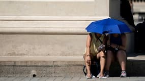 Des personnes utilisent un parapluie pour s'abriter du soleil près de la Pyramide du Louvre lors d'une vague de chaleur, à Paris, le 26 juin 2019