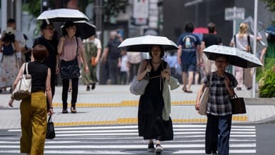 Des piétons se protègent du soleil à Tokyo le 9 juillet 2024 alors que le pays subit une vague de chaleur rare et intense