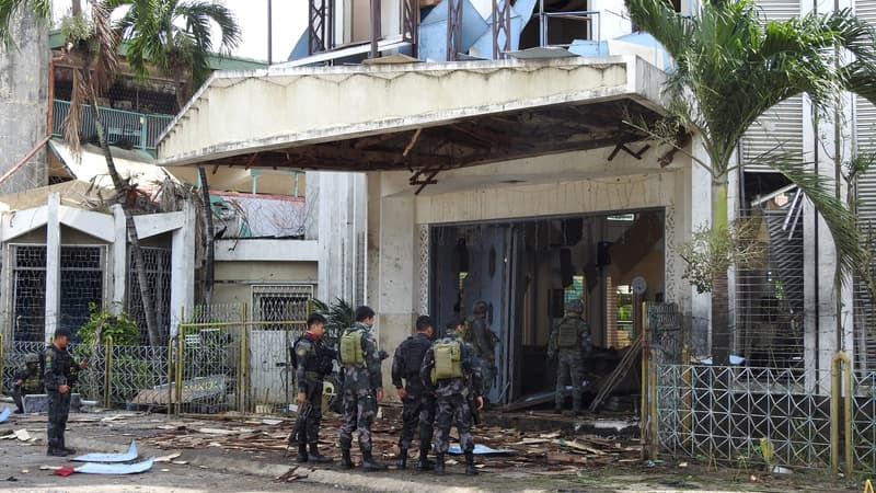 Des policiers et militaires se tiennent devant une cathédrale de l'île de Jolo, dans les Philippines, après l'explosion de deux bombes le 27 janvier 2019. 