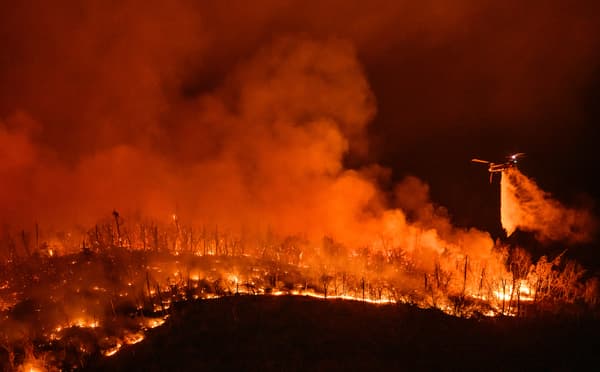 Un hélicoptère de nuit largue de l'eau sur l'incendie de forêt, à Oroville, en Californie, aux États-Unis, le 2 juillet 2024.