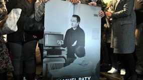 Des collègues et proches tiennent un portrait du professeur Samuel Paty lors d'une marche blanche à Conflans-Sainte-Honorine, le 20 octobre 2020.