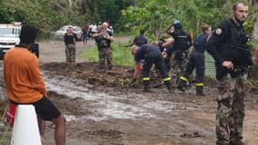 Cette photographie prise le 13 janvier 2025 montre des pompiers et des gendarmes déblayant des débris sur une route après la tempête tropicale Dikeledi, dans le village de Mzouazia, sur le territoire français de l'océan Indien de Mayotte. (Photo d'illustration)