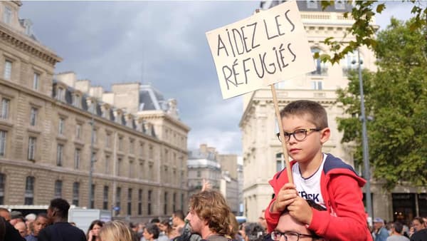 Un petit garçon porte une pancarte: "Aidez les réfugiés"