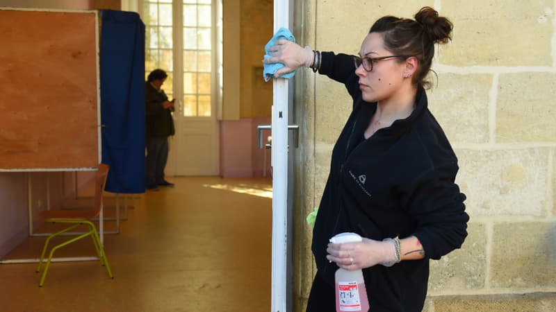 Une femme désinfecte la porte dans un bureau de vote de Bordeaux