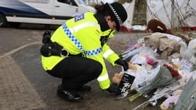 Une policière laisse une carte en hommage à un bébé retrouvé mort à Salford, au Royaume-Uni, le 21 novembre 2024