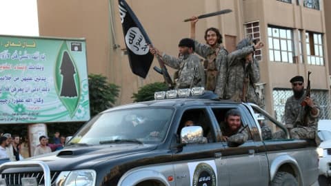 Une photo de propagande diffusée par le média jihadiste Welayat Raqa montre des membres du groupe Etat Islamique paradant dans une rue de Raqa, le 30 juin 2015 en Syrie