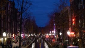Des personnes marchent sur les quais la nuit dans le quartier rouge d'Amsterdam, à l'ouest des Pays-Bas, le 24 novembre 2021.
