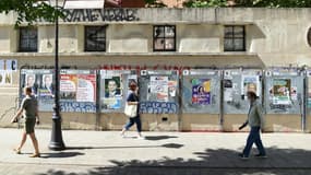 Des passants devant des affiches électorales le jour du 1er tour des régionales, le 20 juin 2021 à Paris