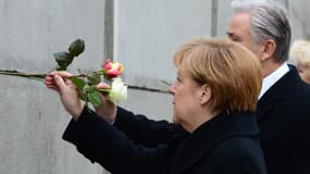 Angela Merkel et Klaus Wowereit, maire de Berlin, déposent une rose dans un morceau du Mur.