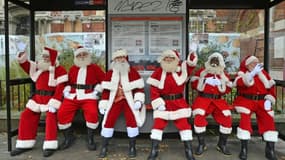 Des Pères Noël font une pause sous un abribus devant leur "école" à Londres, le 30 novembre 2021