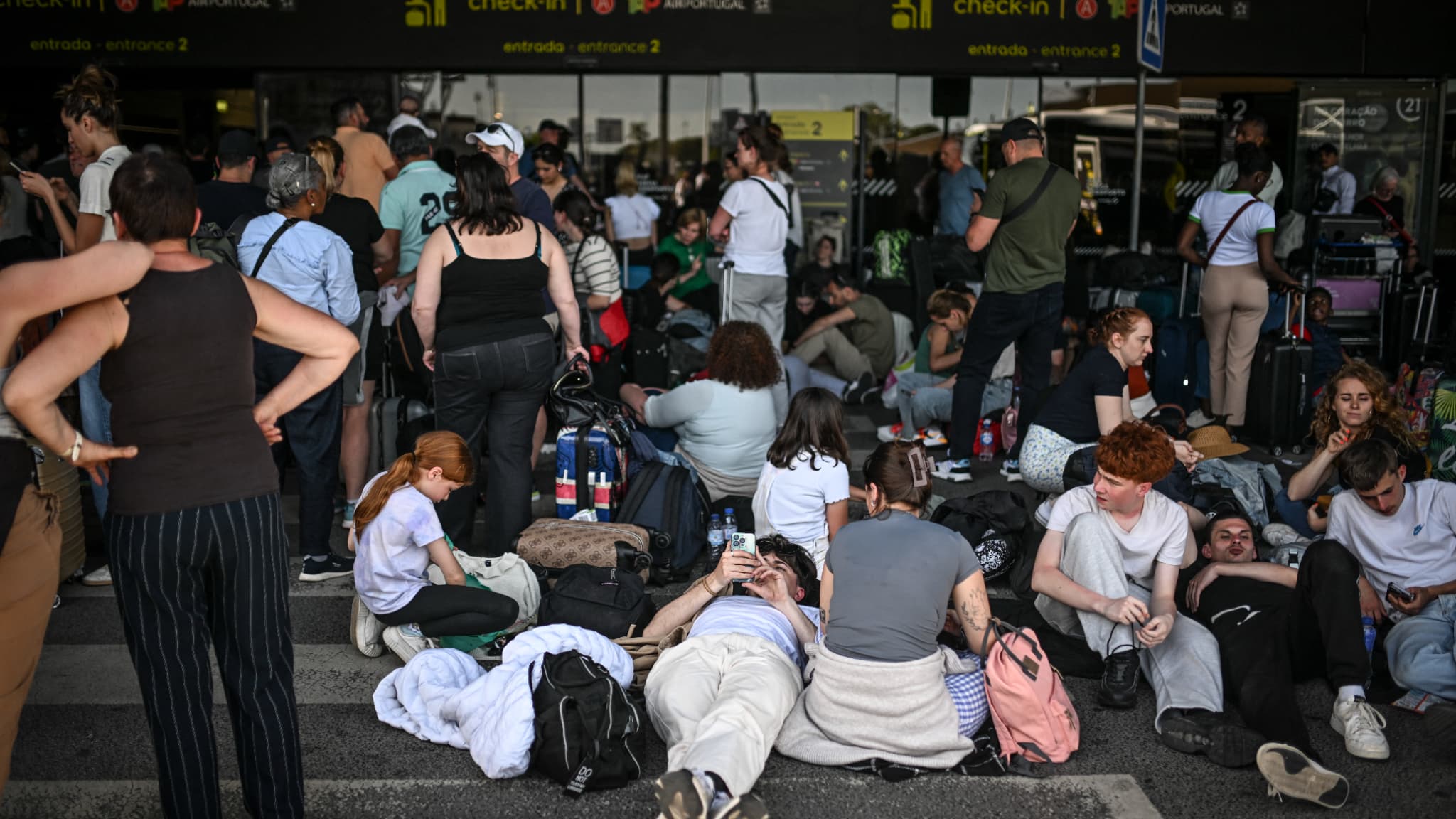 Des passagers avec leurs bagages attendent devant l'aéroport Humberto Delgado après une panne d'électricité générale à Lisbonne le 28 avril 2025. Des passagers avec leurs bagages attendent devant l'aéroport Humberto Delgado après une panne d'électricité générale à Lisbonne le 28 avril 2025.