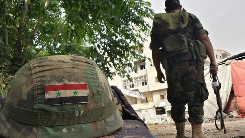 Un soldat syrien posté près d'un casque orné d'un drapeau syrien, à Homs, le 27 mai 2014.