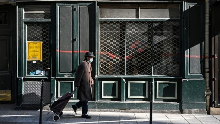 Un passant devant un magasin fermé --car ne faisant pas partie des commerces dits non essentiels--, à Paris le 20 mars 2021 