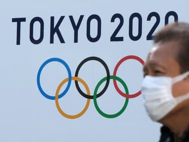 Un homme portant un masque passe devant le logo des Jeux olympiques de Tokyo le 4 février 2021