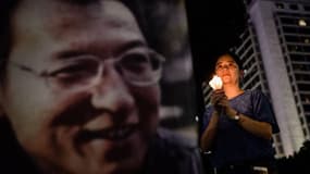 Une femme tient un cierge alors qu'elle assiste à une veillée en l'honneur du pris Nobel de la paix Liu Xiaobo (dont le portrait est sur la bannière) à Hong Kong, le 29 juin 2017.