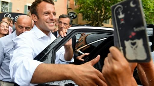 Le président Emmanuel Macron salue la foule après s'être entretenu avec le maire de la commune de Bormes-les-Mimosas (Var), le 27 juillet 2019