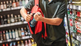 Un homme en train de voler une bouteille d'alcool, image d'illustration
