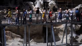 Des touristes visitent le site de restauration de la fontaine de Trevi depuis une promenade le 8 juillet 2014 à Rome. Les travaux de construction ont débuté le 7 octobre 2024 afin de permettre d’importants travaux d’entretien de la fontaine de Trevi. (Photo d'archives)