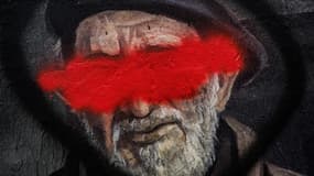 Cette photographie montre un détail de la célèbre fresque lyonnaise de CiteCreation représentant l'abbé Pierre avec son visage barré de rouge, à Lyon dans le centre-est de la France, le 30 septembre 2024.