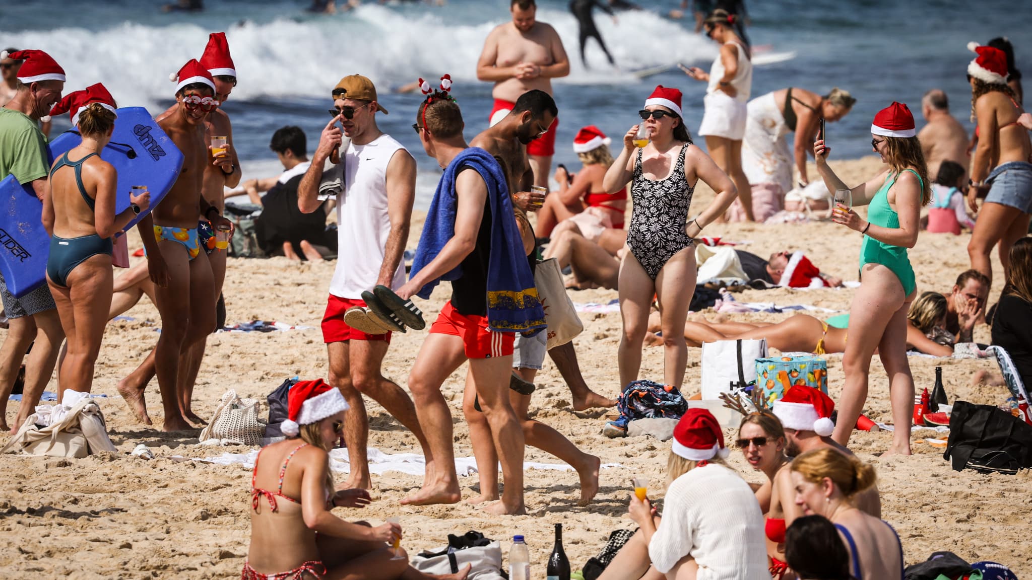 Des Australiens avec des bonnets de père Noël sur la plage de Bondi à Sydney, le 25 décembre 2023.