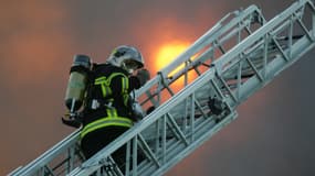 Des pompiers sur une grande échelle interviennent sur un incendie (photo d'illustration)