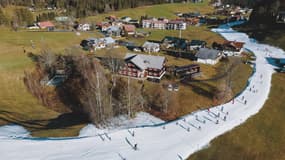 Des skieurs descendant une piste de neige artificielle le long des prairies et des maisons à Riezlern, en Autriche, le 30 décembre 2022.