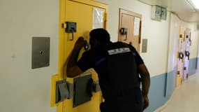 Un agent pénitentiaire regarde par le judas d'une porte à l'intérieur d'une cellule    de l'Unité pour détenus violents de la prison de Fleury-Mérogis, le 21 juin 2023 dans l'Essonne