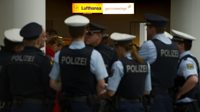 A l'aéroport de Dusseldorf, des policiers allemands protègent des proches des victimes du crash d'un A320 de la compagnie allemande Germanwings.