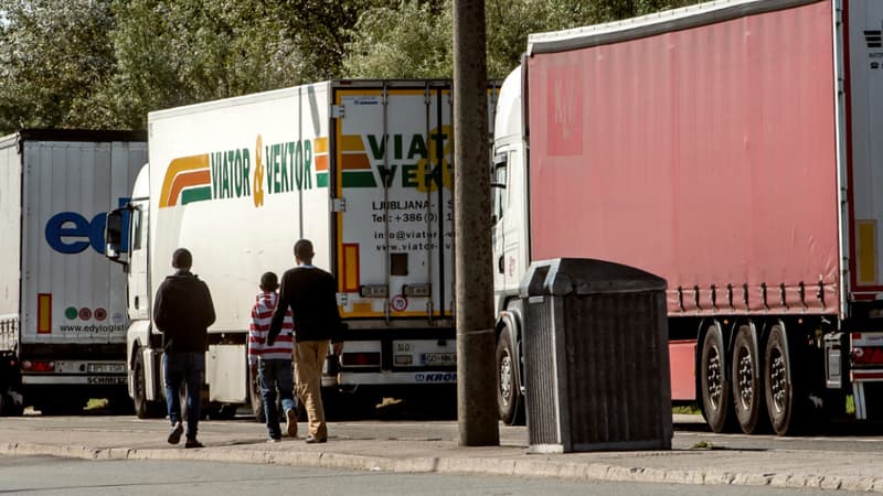 Des migrants marchent à côté de camions stationnés à Calais, le 5 août 2014.