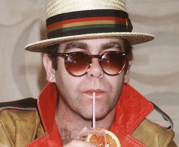 Le chanteur britannique Elton John - de son vrai nom Réginald Kenneth Dwight - buvant un cocktail le 29 mars 1983 à Tunis, avant de recevoir les "lunettes les plus chères du monde", offertes par le joaillier Cartier.