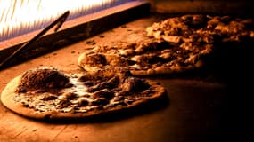 Un boulanger libanais en pleine préparation d'un pain recouvert d'un mélange de thym, de sumac, de graines de sésame grillées, de sel et d'huile d'olive, base du manouché libanais