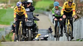 Wout van Aert et Christophe Laporte suivis par un cycliste amateur, les yeux sur son compteur, dans le Vieux Quaremont, le 30 mars 2023