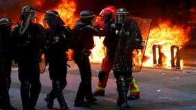 Des CRS près en position près d'une station de vélos en libre-service incendiée lors d'une manifestation contre la réforme des retraites, le 1er mai 2023 à Paris