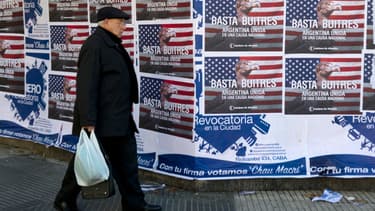 Un homme marche devant des affiches qui fustigent les fonds vautours à Buenos Aires.