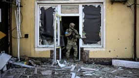 Un soldat ukrainien sort d'un bâtiment bombardé à Kiev, le 12 mars 2022 